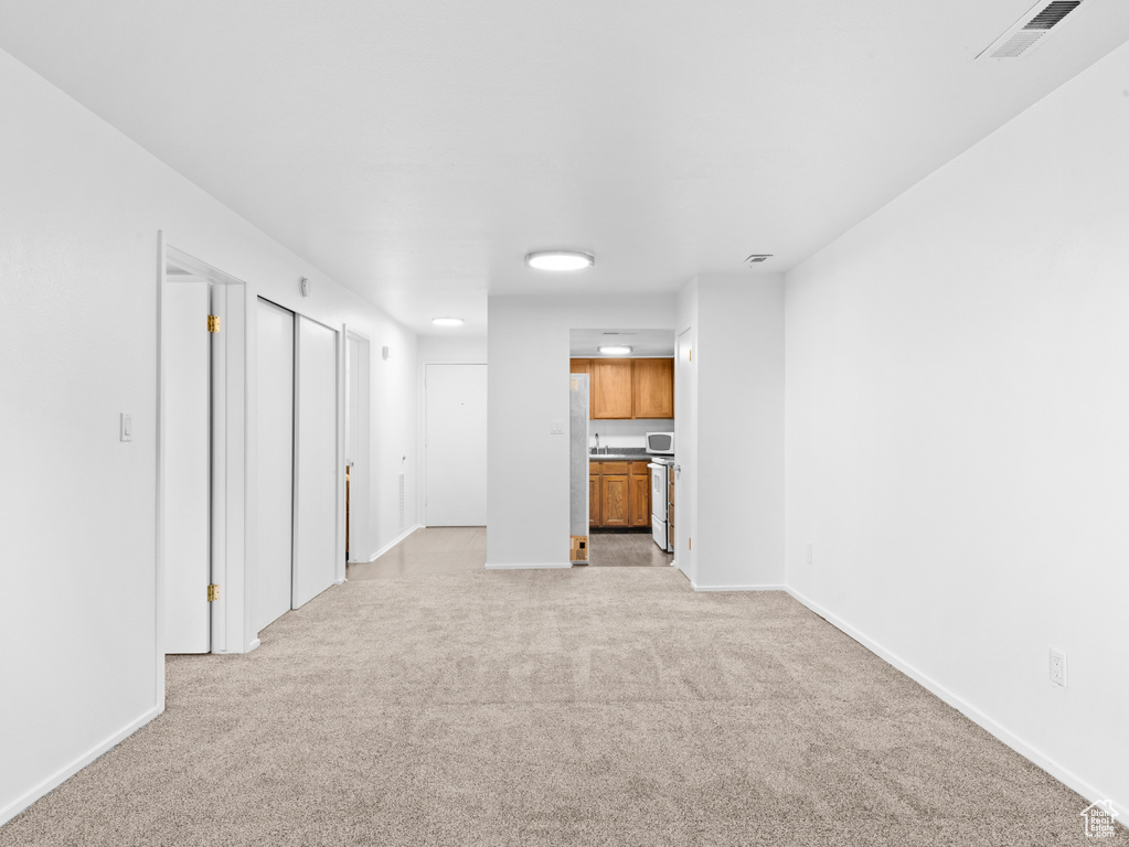 Unfurnished living room featuring light carpet