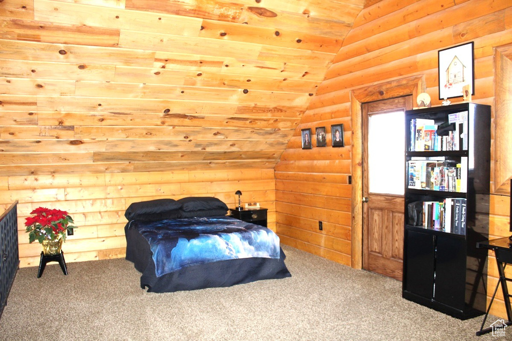 Bedroom with lofted ceiling, carpet floors, and wood walls