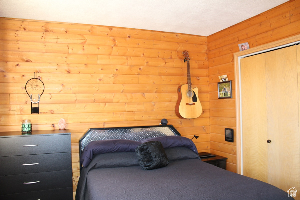 Bedroom featuring a closet and wood walls