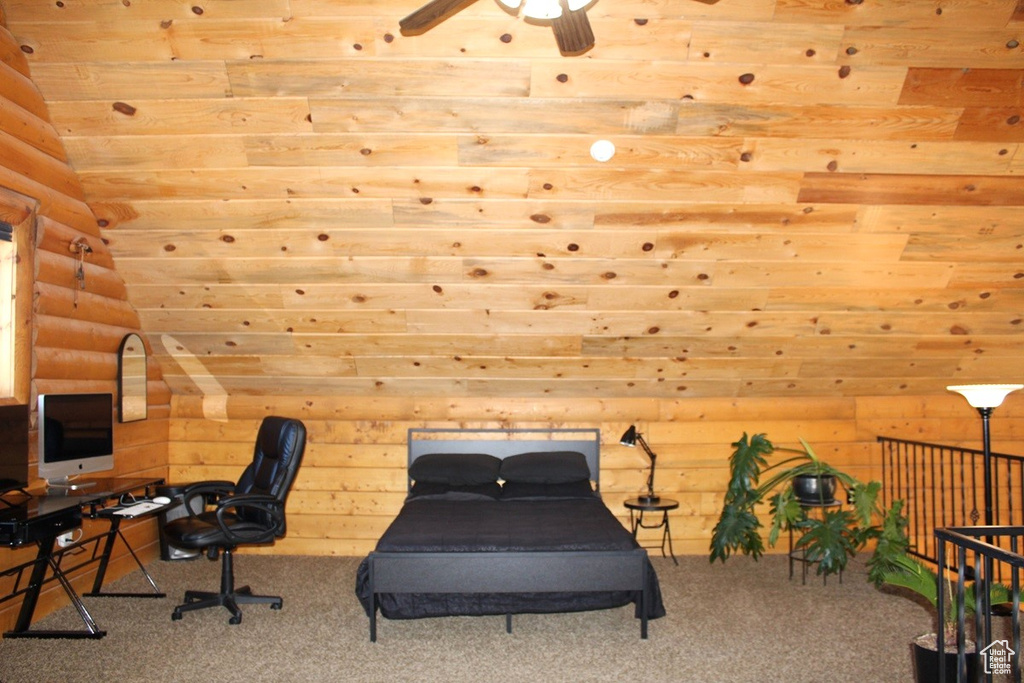 Office area with carpet, rustic walls, and ceiling fan