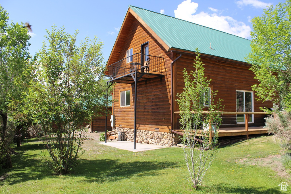 Back of property featuring a balcony, a lawn, metal roof, a deck, and log veneer siding