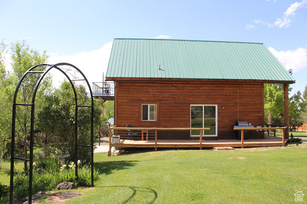 Rear view of house with a wooden deck, a yard, and metal roof