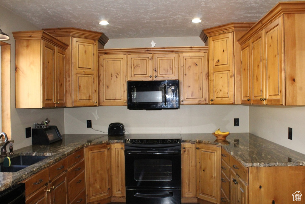 Kitchen with dark stone countertops, sink, a textured ceiling, and black appliances