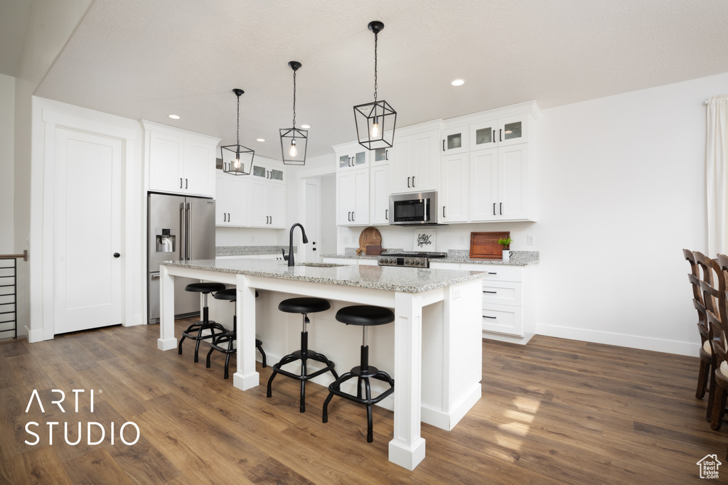 Kitchen with sink, a breakfast bar area, white cabinets, stainless steel appliances, and a center island with sink