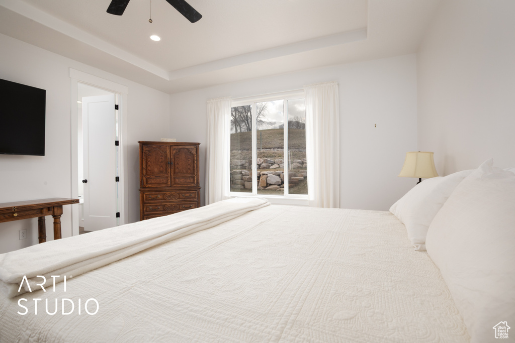 Bedroom with a raised ceiling and ceiling fan