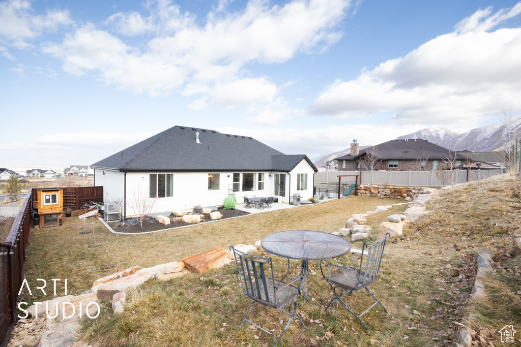 Rear view of house featuring a mountain view, a yard, and a patio area