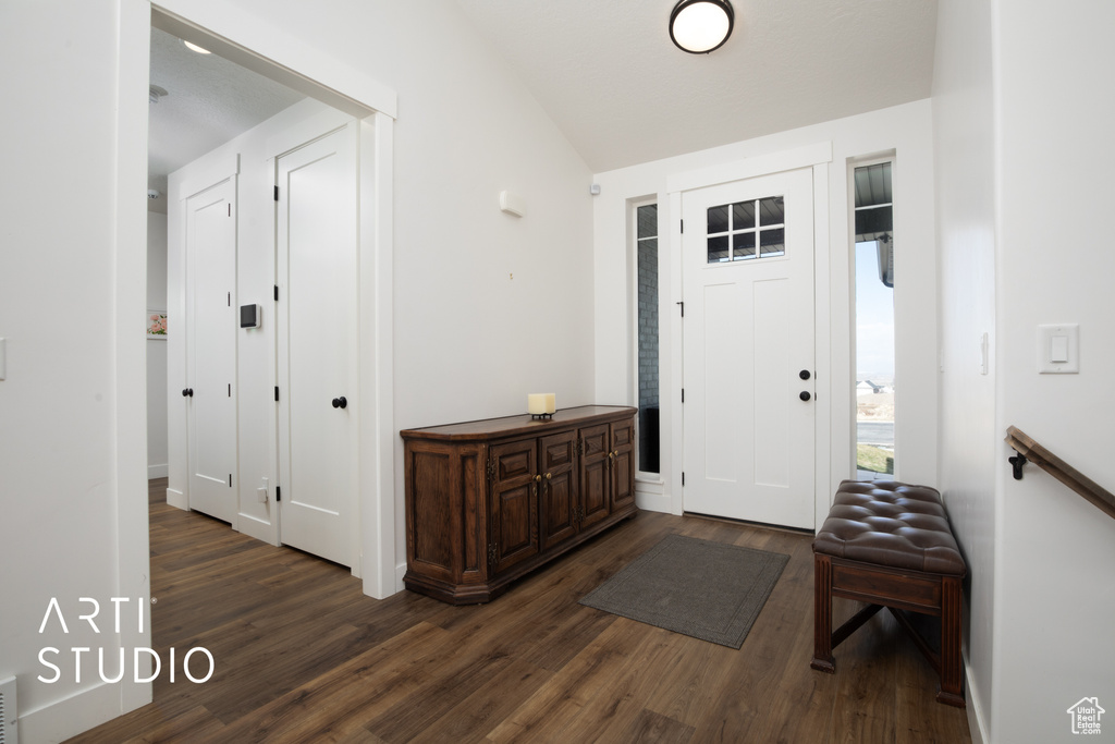 Entrance foyer with dark wood-type flooring and vaulted ceiling