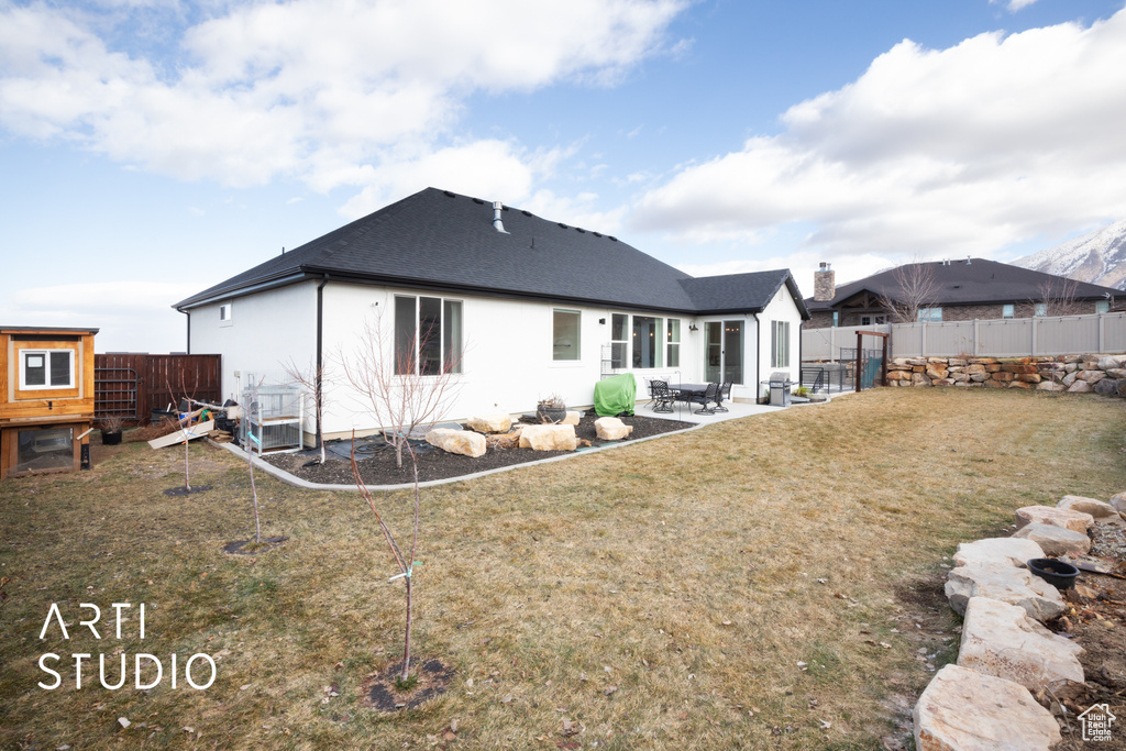 Back of house with a patio and a lawn