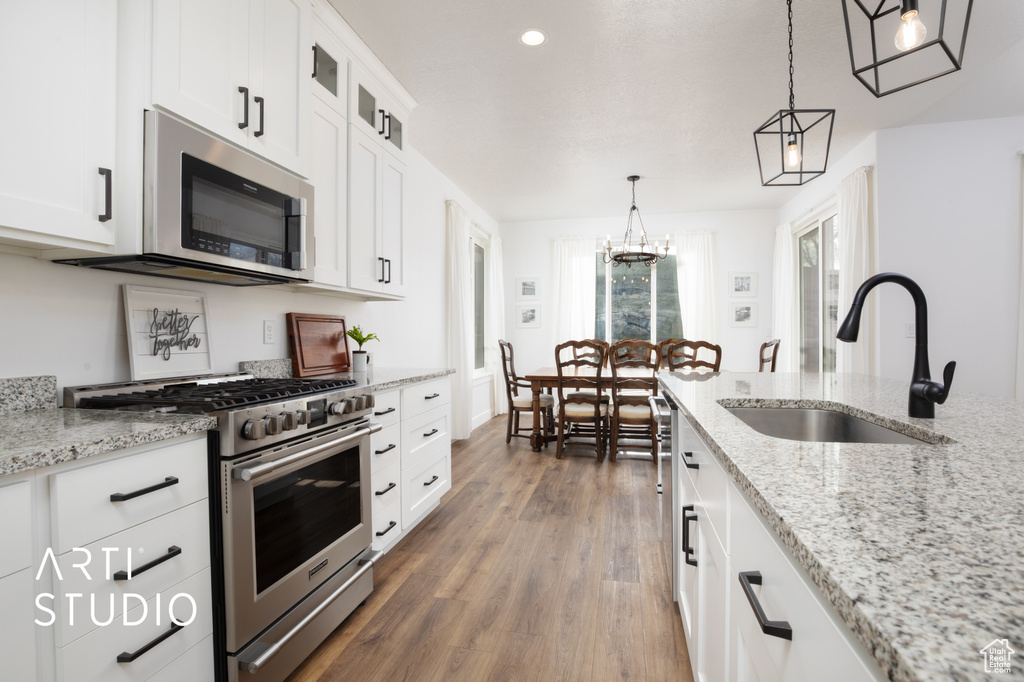 Kitchen with sink, decorative light fixtures, stainless steel appliances, and white cabinets