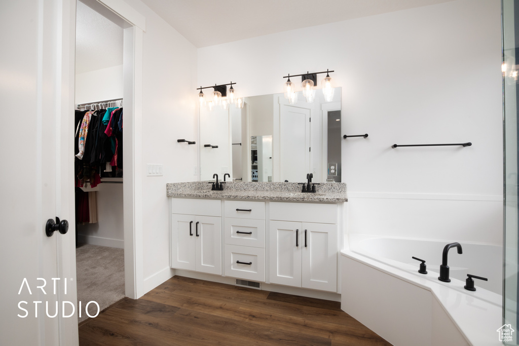 Bathroom with vanity, hardwood / wood-style floors, and a tub