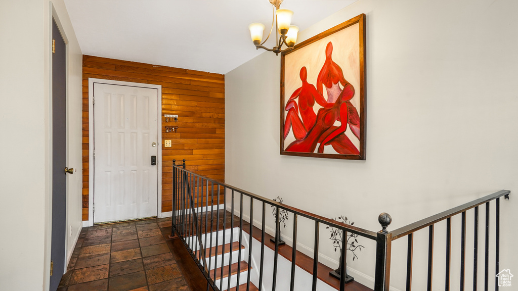 Stairway with wooden walls, stone finish floors, and a chandelier