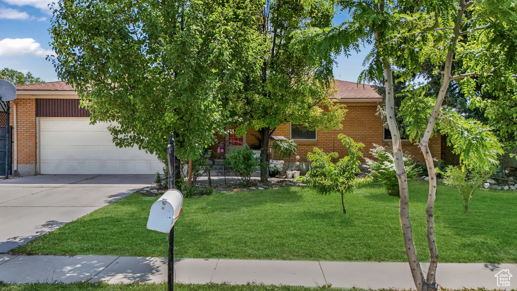 Obstructed view of property with brick siding, a garage, a front yard, and concrete driveway