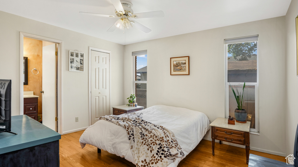 Bedroom featuring light wood-type flooring, a closet, ensuite bathroom, and ceiling fan