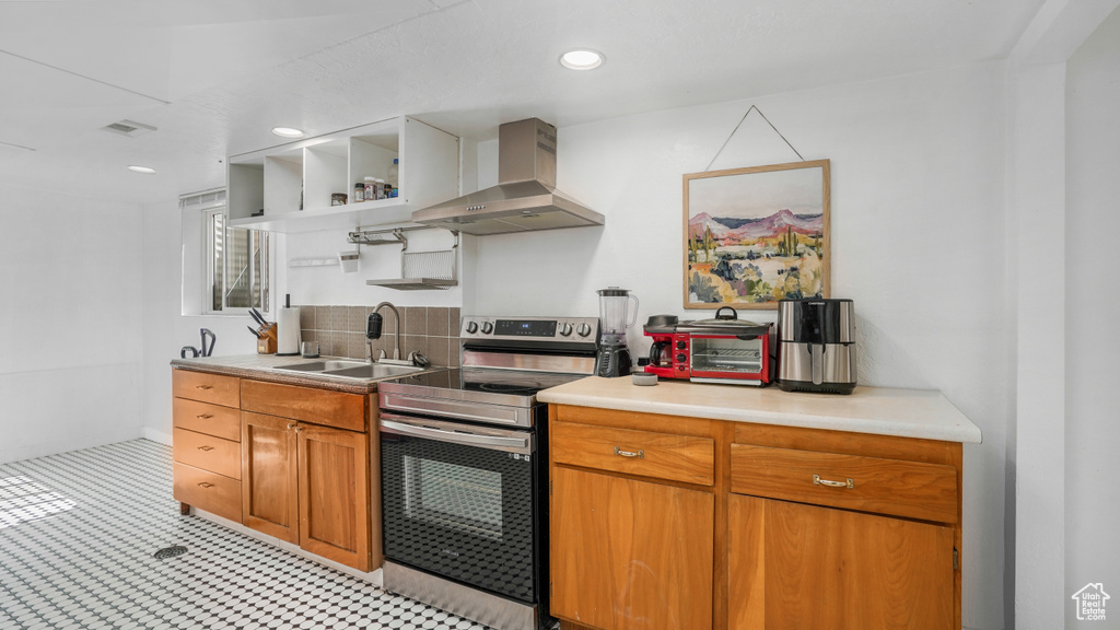 Kitchen featuring wall chimney exhaust hood, electric range, open shelves, light countertops, and brown cabinets