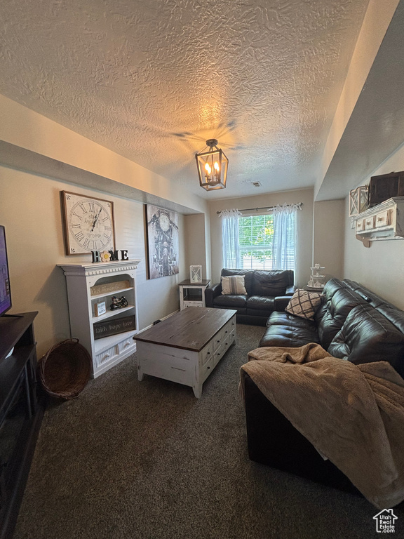Living area with a textured ceiling, dark colored carpet, and a chandelier