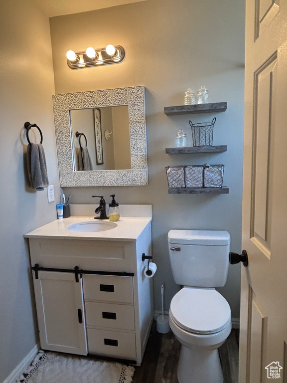 Half bathroom with baseboards, vanity, and toilet