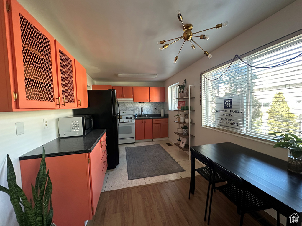 Kitchen featuring sink, light hardwood / wood-style flooring, gas range gas stove, backsplash, and black fridge