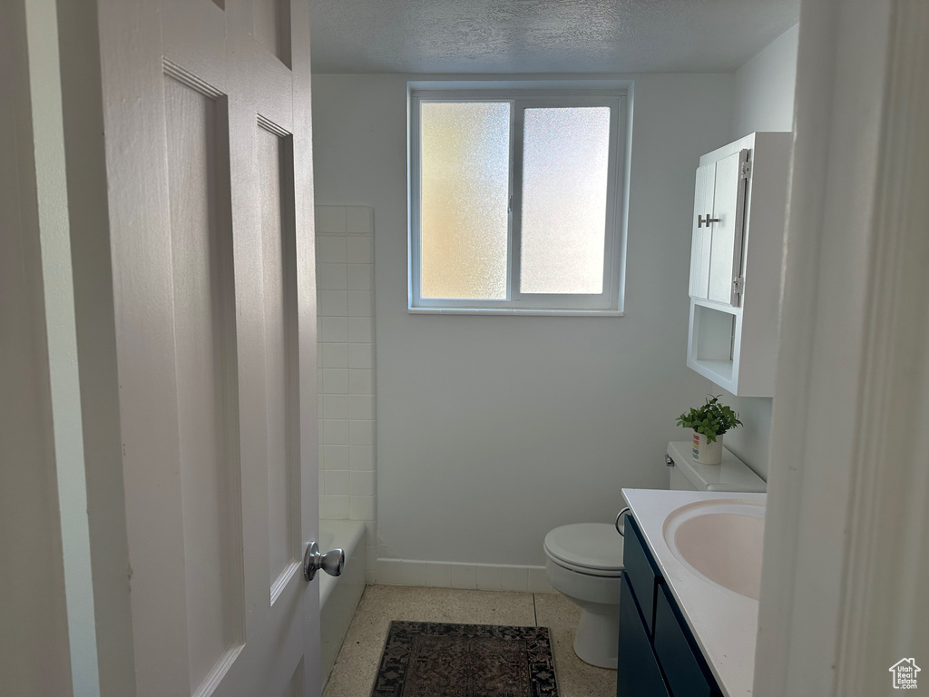 Bathroom with vanity, a textured ceiling, baseboards, and toilet
