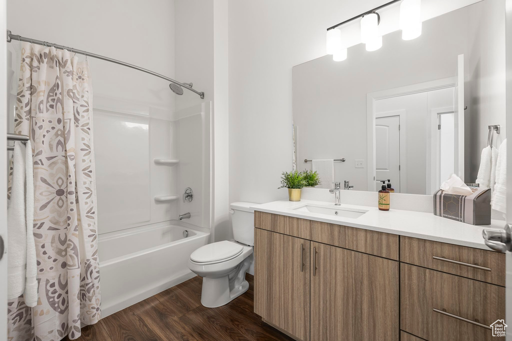 Full bathroom featuring vanity, hardwood / wood-style flooring, shower / bath combination with curtain, and toilet