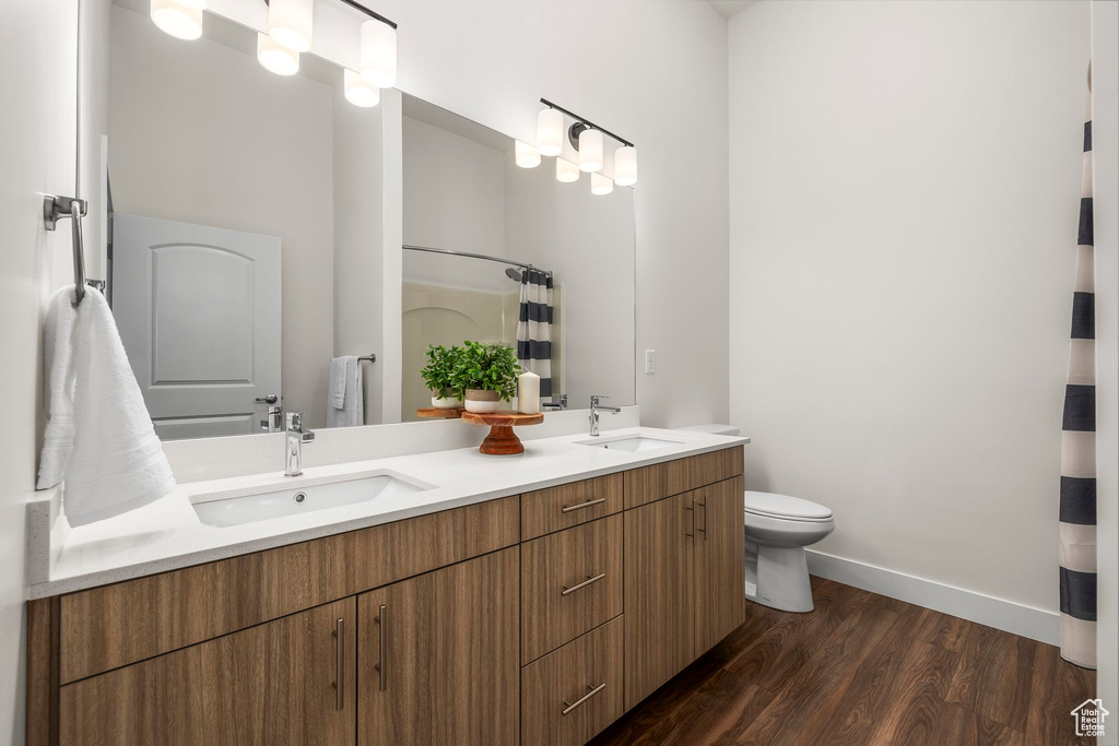 Bathroom featuring wood-type flooring, curtained shower, vanity, and toilet