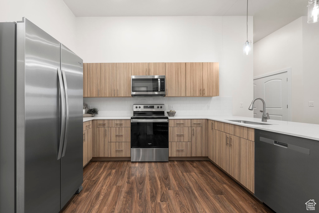 Kitchen featuring pendant lighting, sink, appliances with stainless steel finishes, backsplash, and dark hardwood / wood-style floors