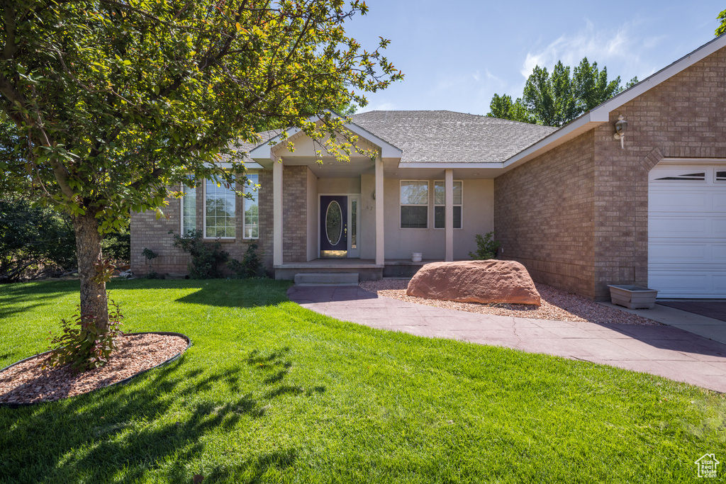 Single story home with brick siding, a front yard, and a shingled roof