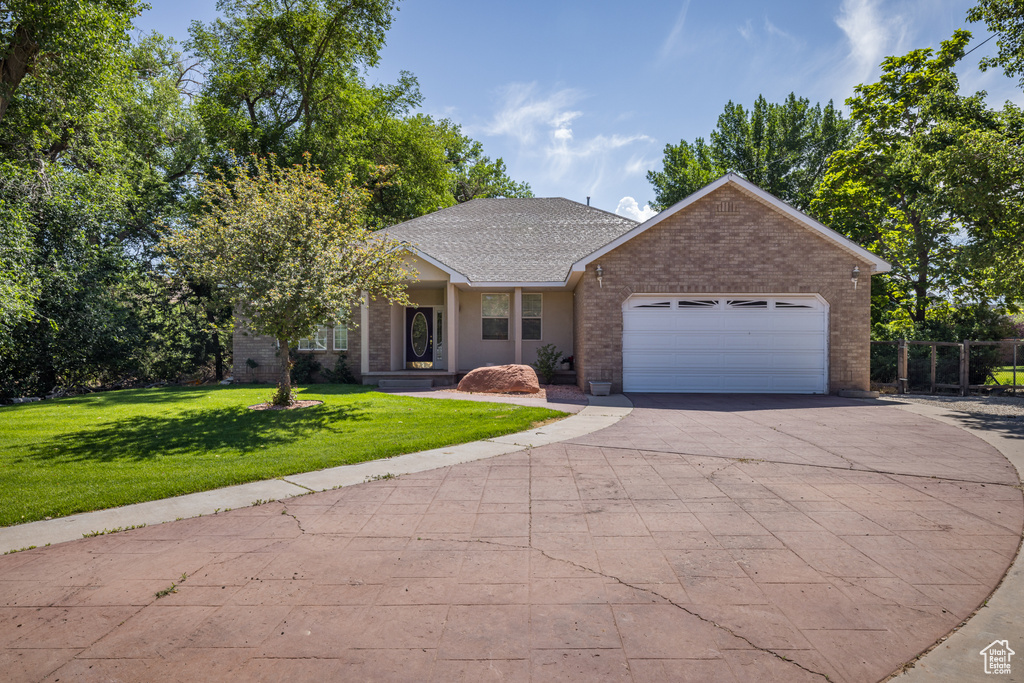 View of front facade with brick siding, asphalt driveway, a garage, a front yard, and roof with shingles