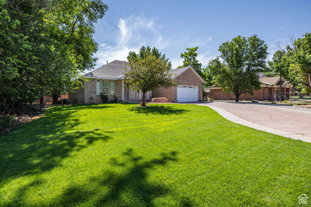 View of front facade featuring driveway, a front lawn, brick siding, and a garage