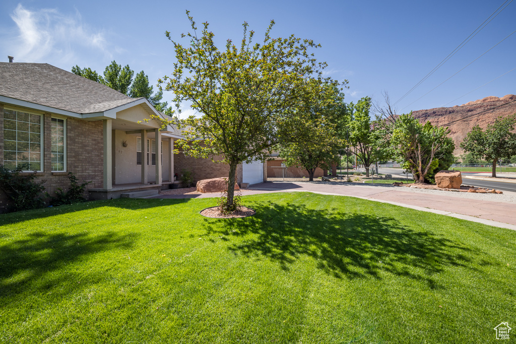View of grassy yard featuring driveway and a mountain view