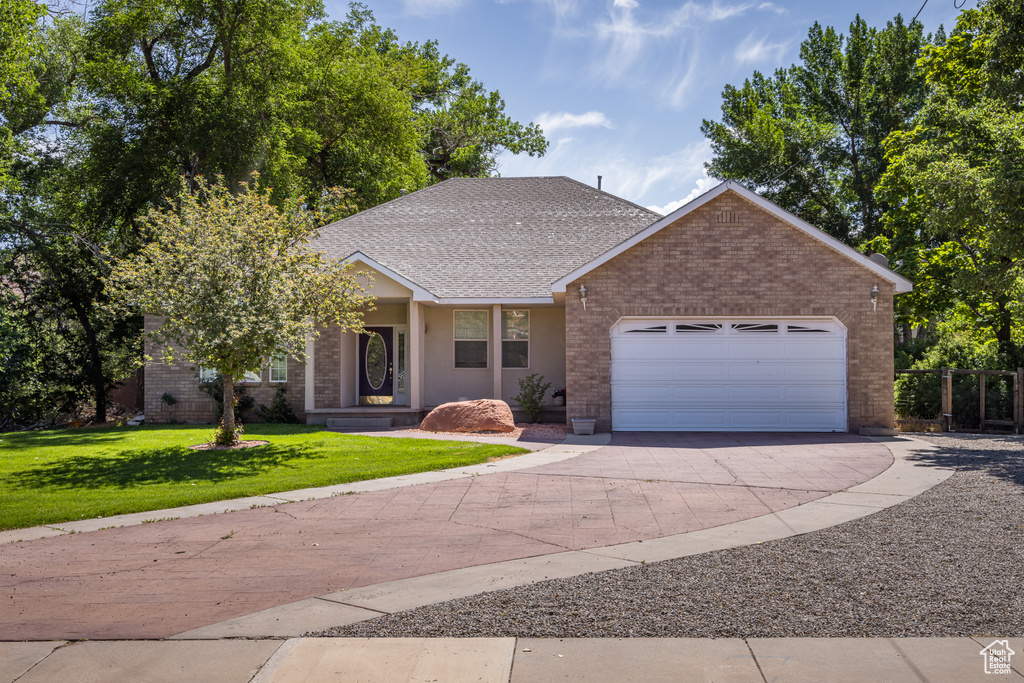 View of front of house with concrete driveway, a garage, brick siding, a front lawn, and a shingled roof