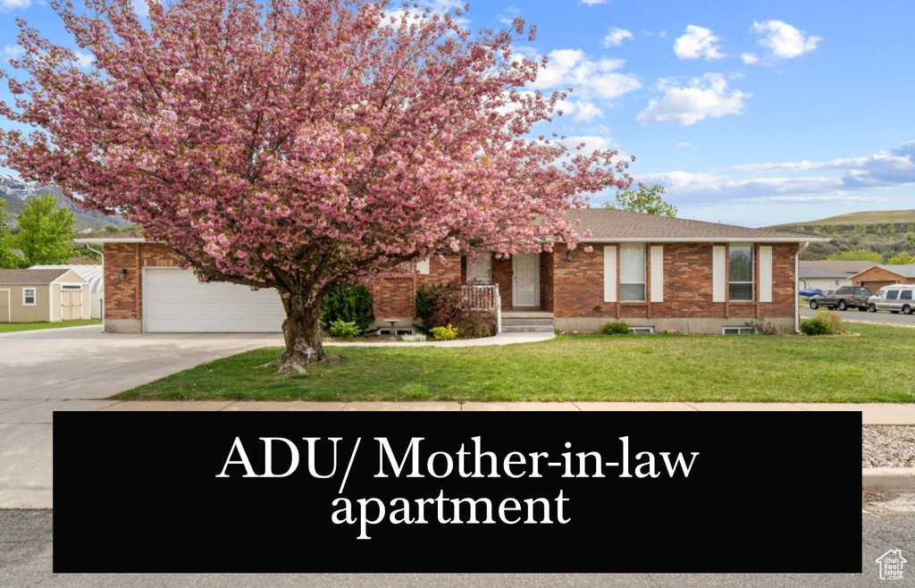 View of front of home featuring brick siding, concrete driveway, a front yard, and a mountain view
