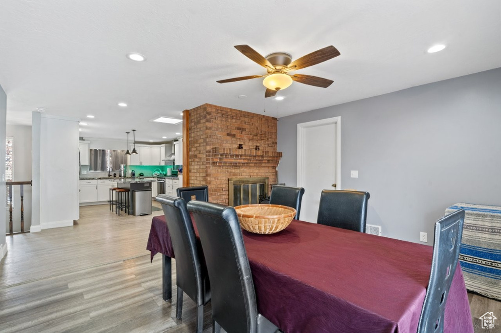 Dining area featuring a ceiling fan, visible vents, a fireplace, light wood-type flooring, and recessed lighting
