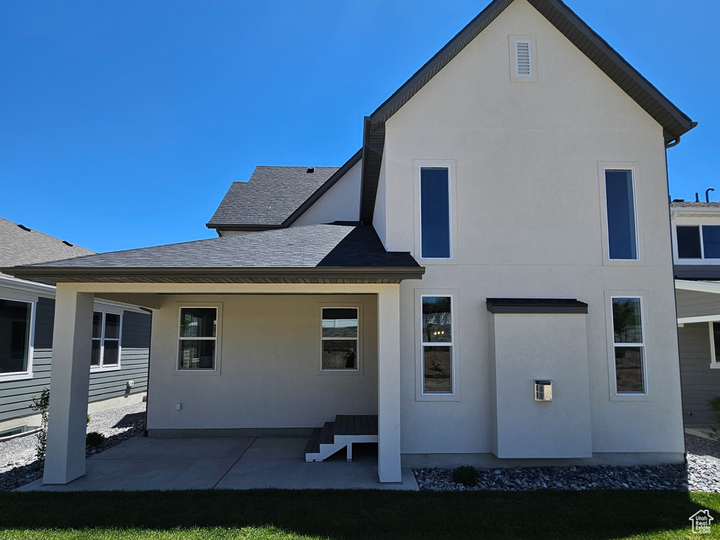 Back of property featuring a lawn, a patio area, and stucco siding