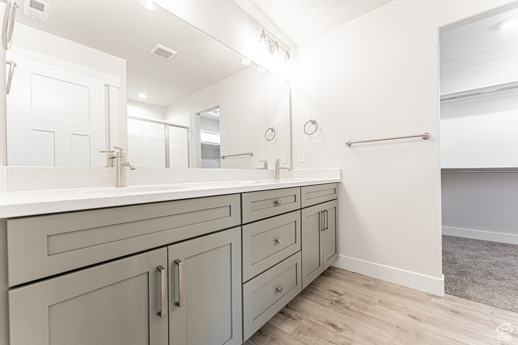 Bathroom with double vanity, a shower stall, baseboards, and a spacious closet