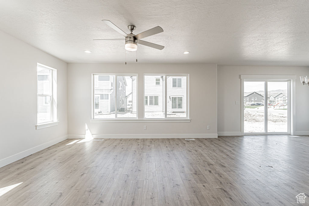 Spare room with a textured ceiling, healthy amount of natural light, light wood-type flooring, ceiling fan, and recessed lighting