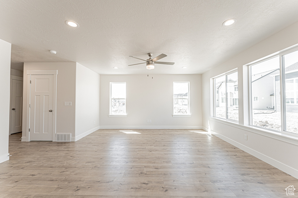 Spare room with healthy amount of natural light, a ceiling fan, baseboards, light wood-style floors, and recessed lighting