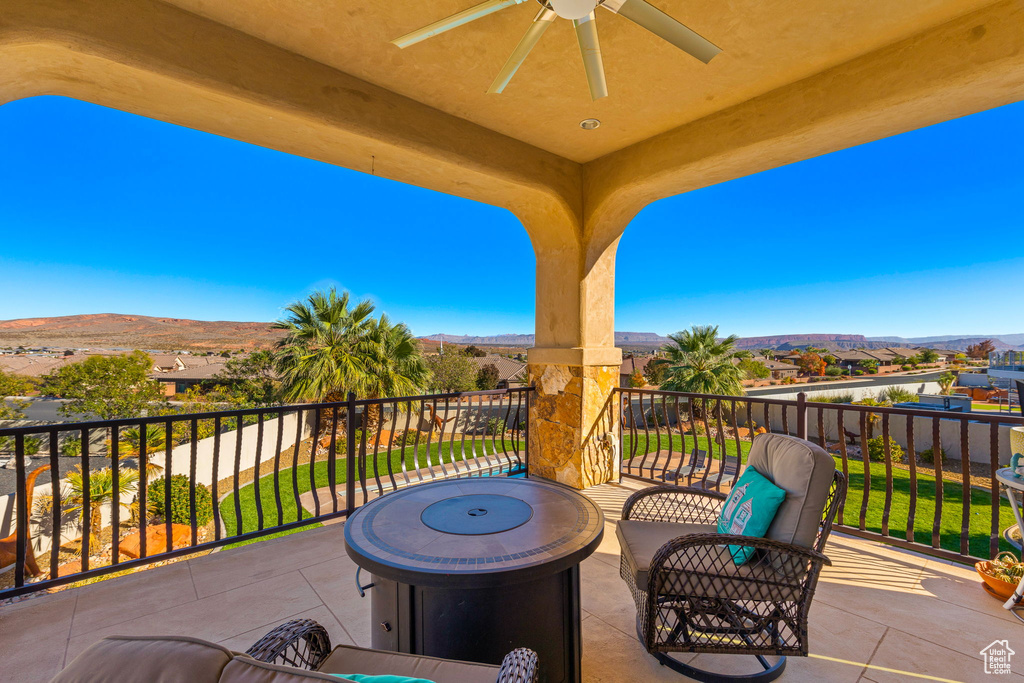 View of patio featuring a mountain view, a balcony, ceiling fan, and an outdoor fire pit