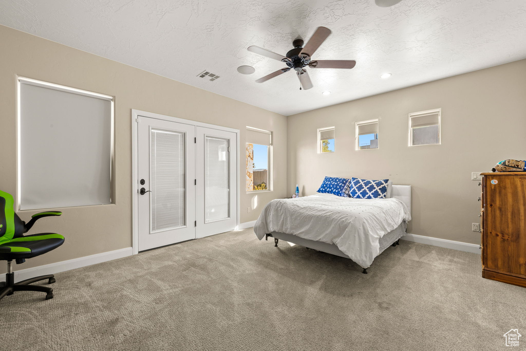 Carpeted bedroom with ceiling fan and a textured ceiling