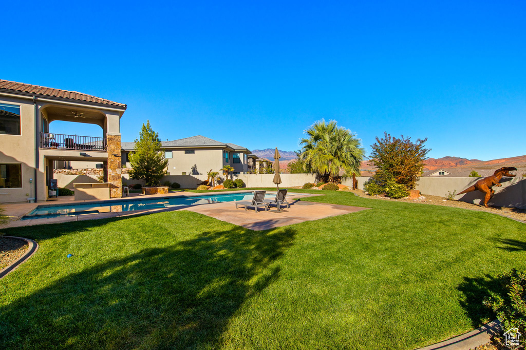 View of yard with ceiling fan, a balcony, a fenced in pool, and a patio