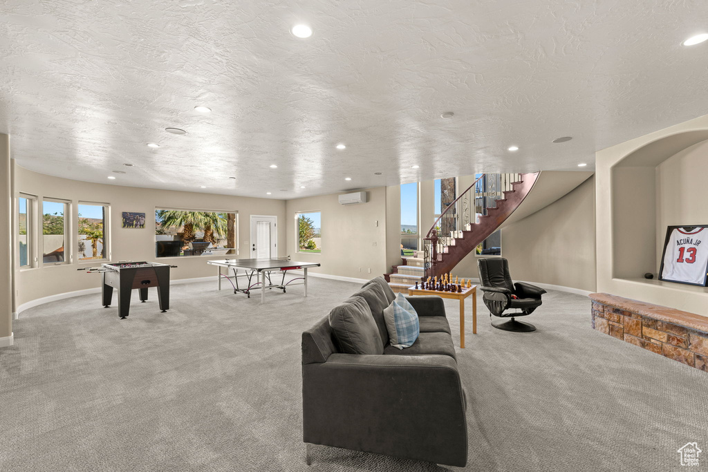 Living room featuring a wall mounted AC, light carpet, and a textured ceiling