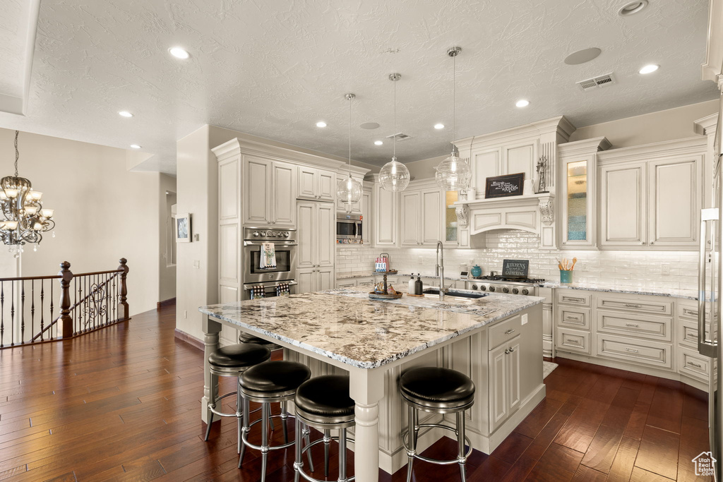 Kitchen featuring a large island, hanging light fixtures, stainless steel appliances, and sink