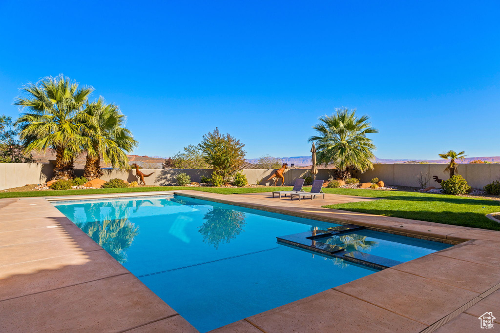 View of pool with a patio area and a lawn