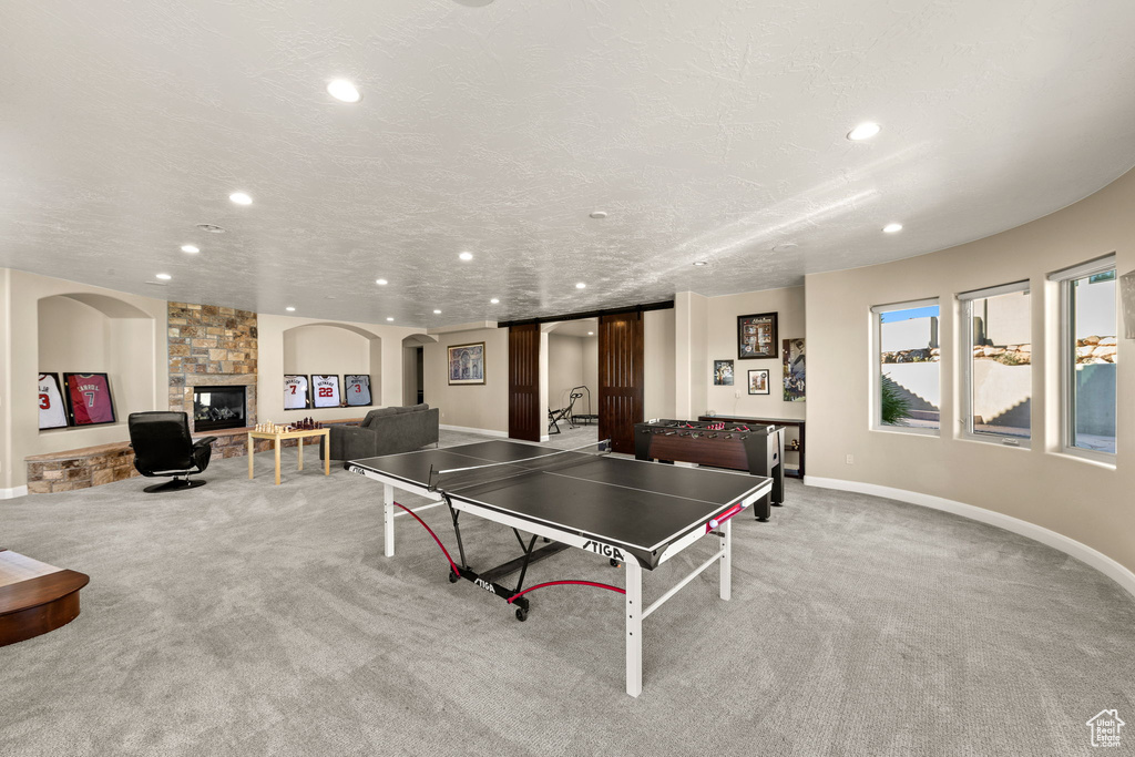 Playroom with a fireplace, light carpet, and a textured ceiling