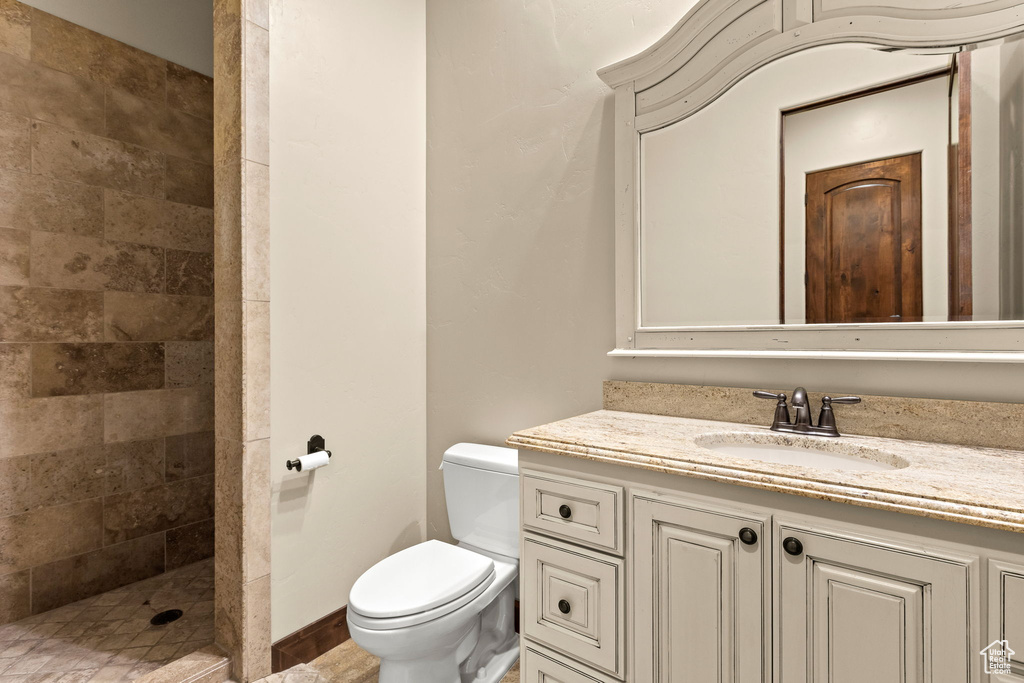 Bathroom with vanity, tiled shower, and toilet