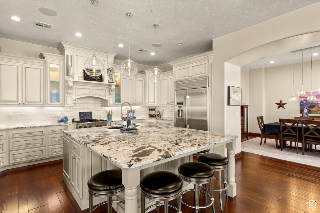 Kitchen featuring sink, hanging light fixtures, a center island, light stone counters, and stainless steel appliances