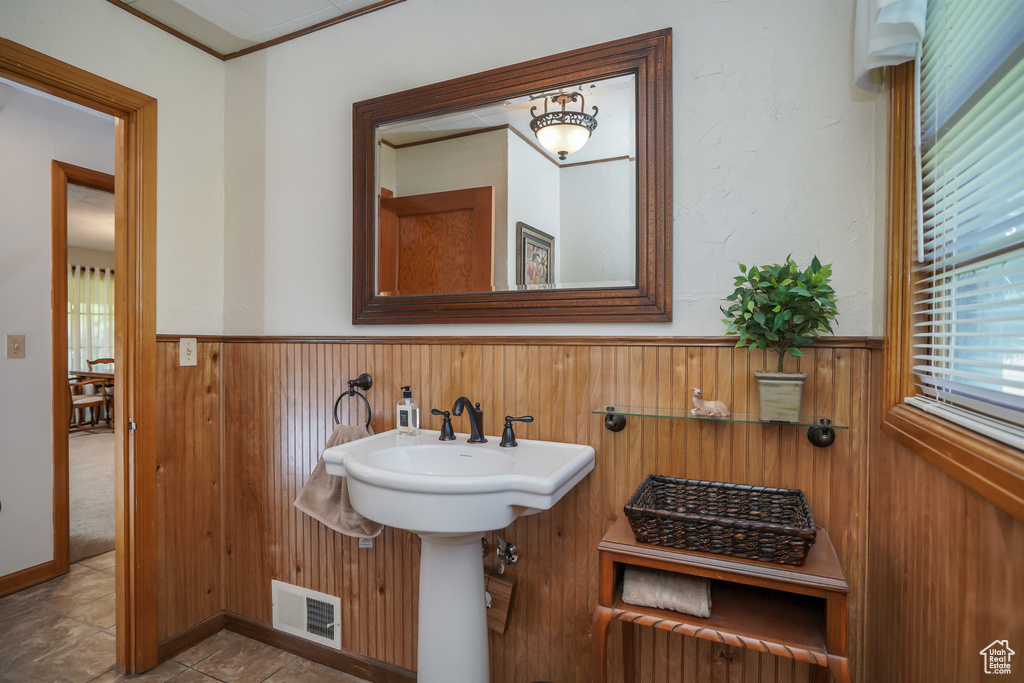 Bathroom featuring crown molding and wooden walls