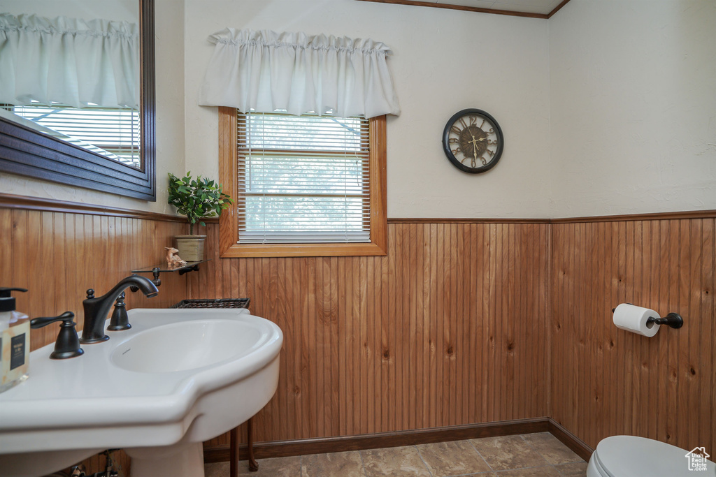 Bathroom featuring toilet, wooden walls, and sink