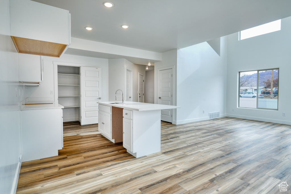 Kitchen featuring white cabinetry, sink, a center island with sink, and light hardwood / wood-style floors