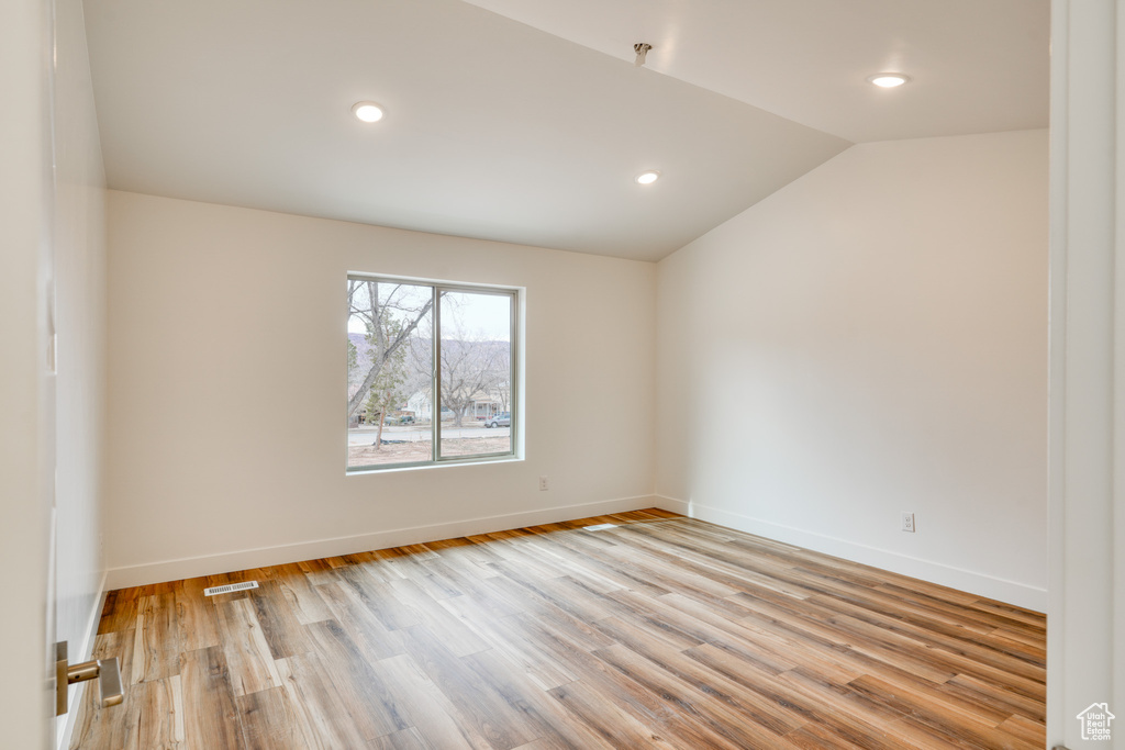 Unfurnished room featuring vaulted ceiling and light hardwood / wood-style floors