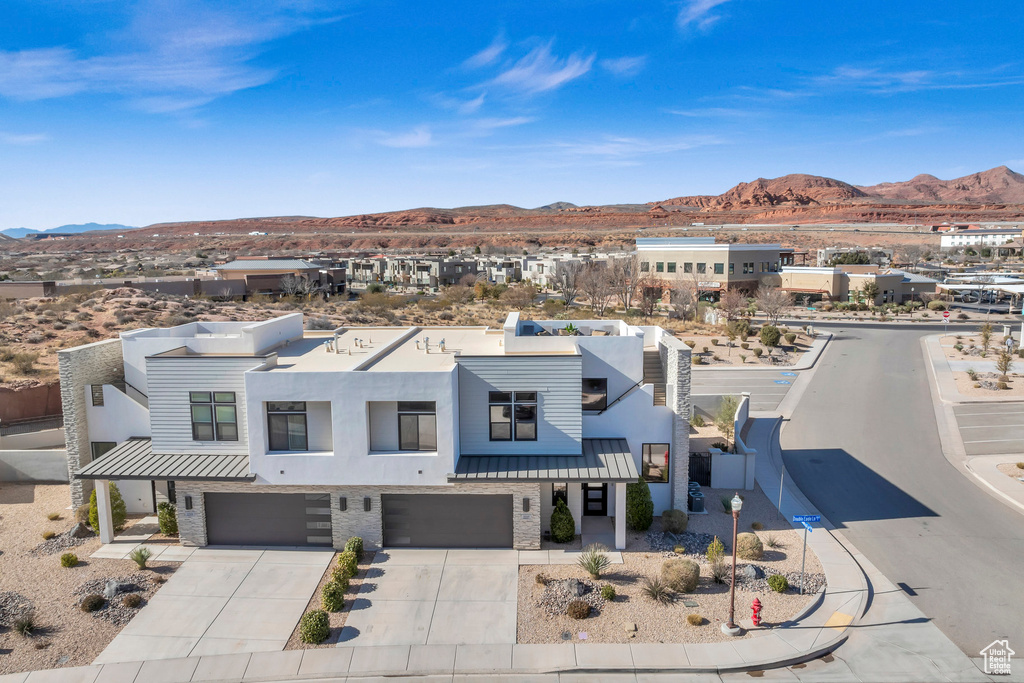 View of front facade with a mountain view, a standing seam roof, an attached garage, and driveway